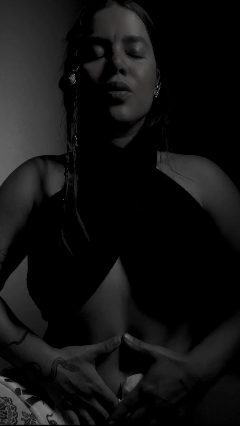 Mujer en blanco y negro, con los ojos cerrados y las manos en triángulo sobre el vientre bajo.