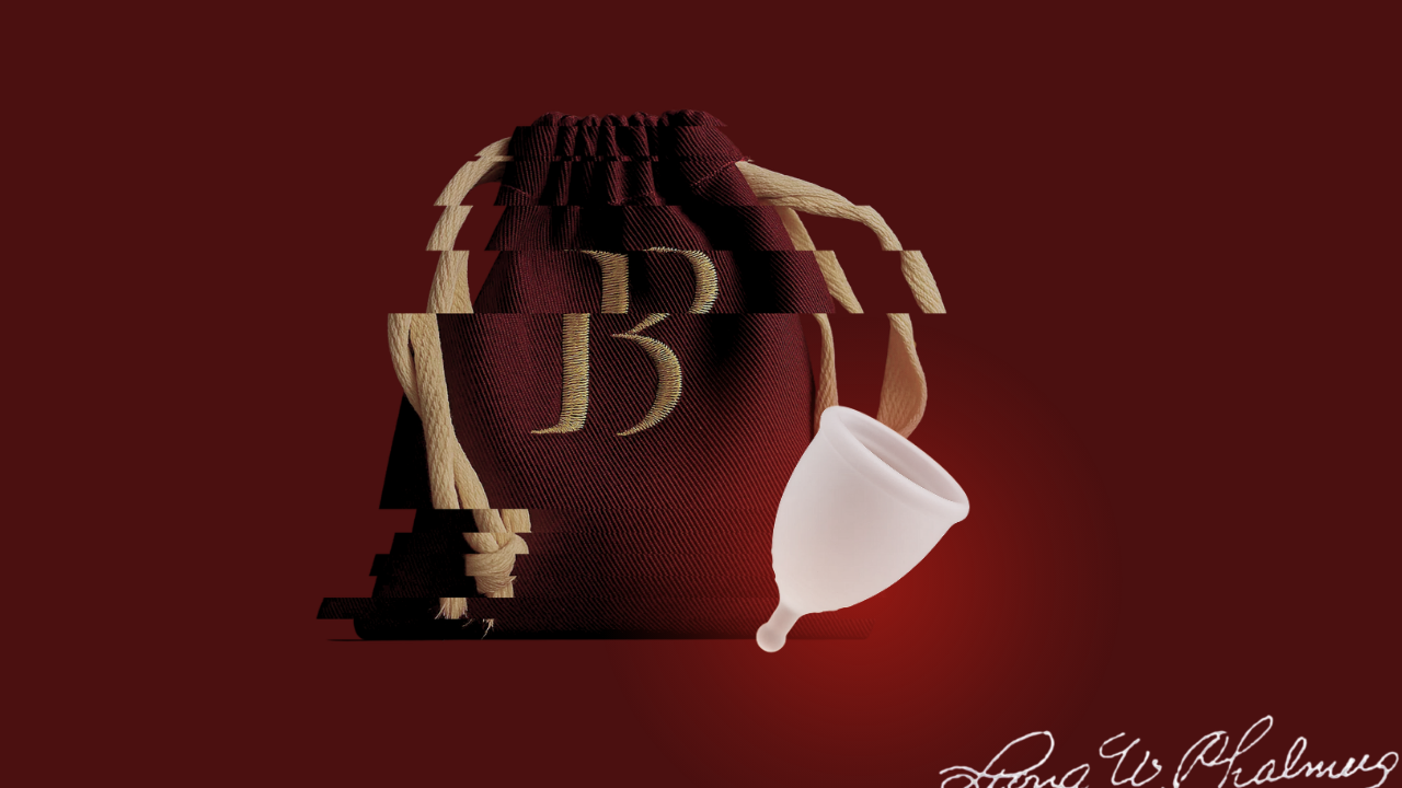 Copa menstrual translúcida junto a su bolsa de tela color vino con cordón crudo y monograma dorado.